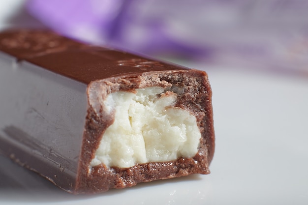 Una barra de chocolate medio mordida con relleno se encuentra sobre la mesa macro foto fondo borroso