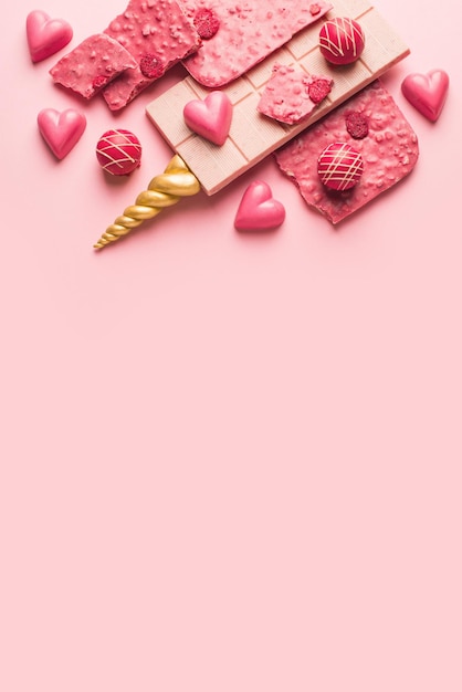Barra de chocolate rosa con cuerno de unicornio dorado y corazón de caramelo Tema de San Valentín y celebración Vista superior del espacio de copia