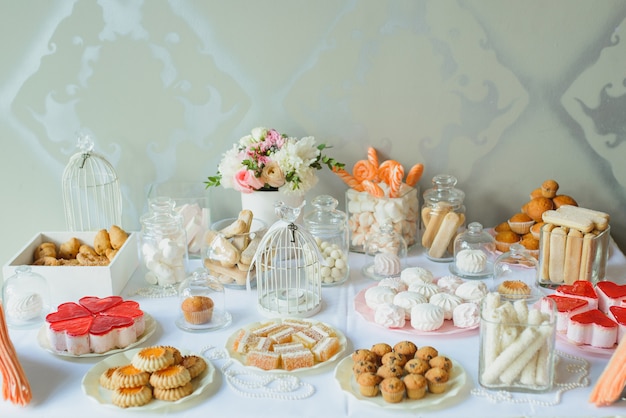 Barra de chocolate brilhante e delicada em um casamento ou festa. biscoitos, doces, marshmallows e flores em cima da mesa