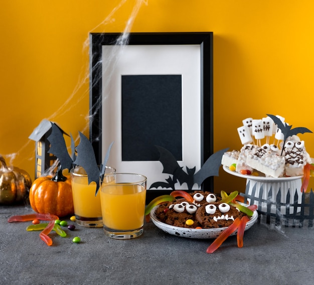 Foto barra de chocolate de halloween: monstros engraçados feitos de biscoitos com minhocas de chocolate e goma, close-up de marshmelow fantasmas na mesa