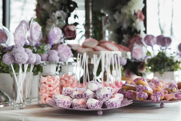 Barra de chocolate rosa para a celebração do feriado. Buffet de doces para festa de aniversário ou casamento. Variedade de sobremesas em fundo de madeira, conceito de catering