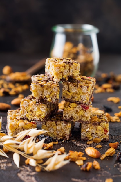 Barra de granola de cereales con nueces, frutas y bayas en la mesa de piedra oscura. Barra de granola. Refrigerio saludable. Vista superior.