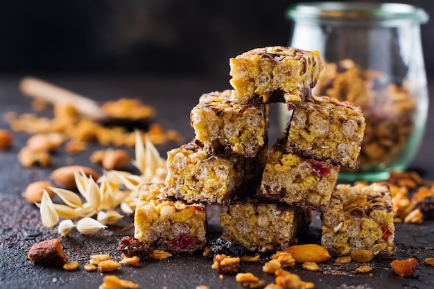 Barra de granola de cereales con nueces, frutas y bayas en la mesa de piedra oscura