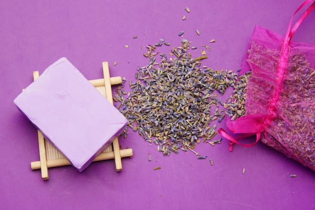 Barra de jabón natural casero y flor de lavanda sobre fondo púrpura