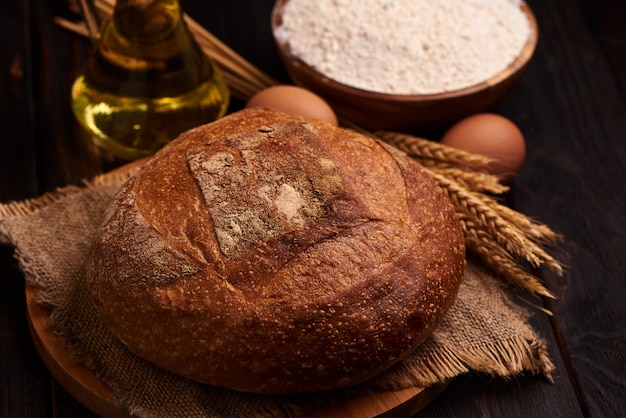 Barra de pan en un fondo de madera, primer de la comida. Contra el fondo de harina y aceite vegetal con huevos.