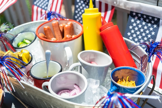 Barra de perritos calientes con mazorcas de maíz para la celebración del 4 de julio en el patio trasero.