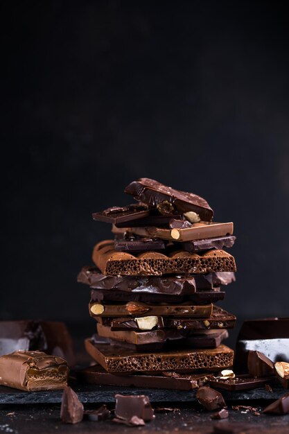 Barra de piezas de la torre de chocolate Trozos oscuros de avellanas y almendras de chocolate roto Concepto de fotografía de comida dulce