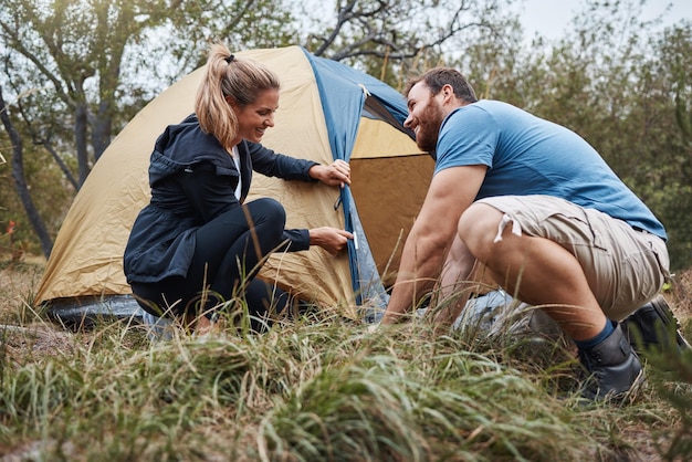 Barraca de acampamento e amor com um casal na natureza para uma aventura divertida ou união no deserto Viagem na floresta e caminhadas com um homem e uma mulher montando seu acampamento em uma escapada de fim de semana