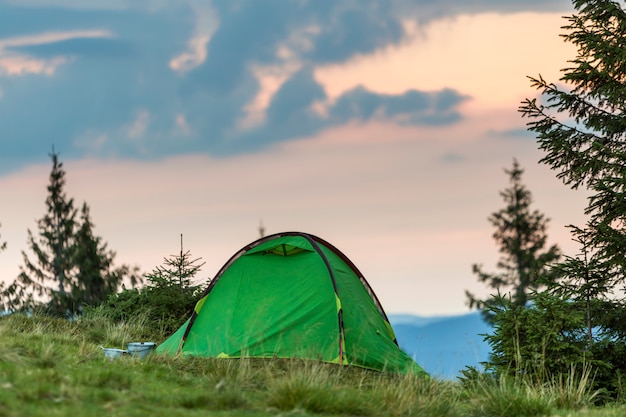 Barraca do turista pequeno na colina da montanha gramada. Verão acampar nas montanhas ao amanhecer. Conceito de turismo.