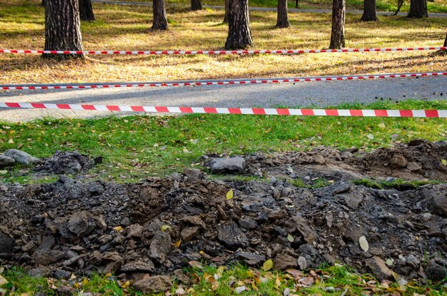 Barragem de fita listrada ao redor do poço e um gramado escavado garantindo a segurança no local do trabalho de reparo