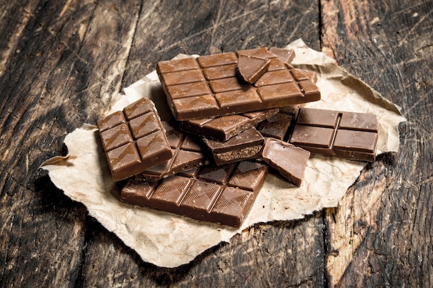 Barras de chocolate rotas en la mesa de madera.