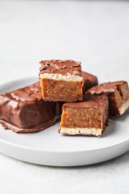 Las barras crudas del chocolate de las fechas del cacao del vegano en el fondo blanco.