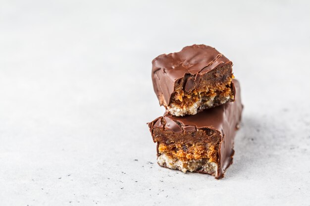 Las barras crudas del chocolate de las fechas del cacao del vegano en el fondo blanco.