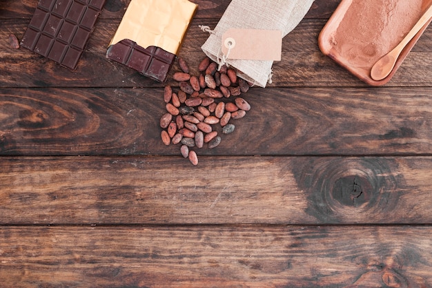 Barras de chocolate, cacau e pó na mesa de madeira