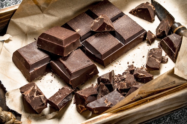 Barras de chocolate com cacau em pó sobre fundo de madeira