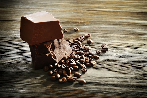Barras de chocolate com grãos de café em fundo de madeira