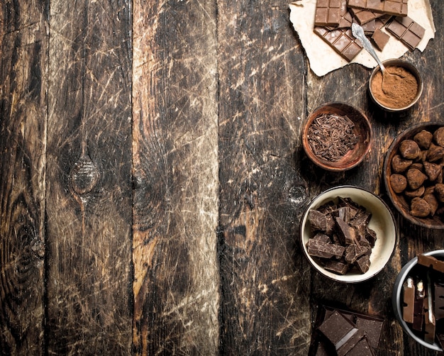 Barras de chocolate com trufas e cacau em pó em fundo de madeira