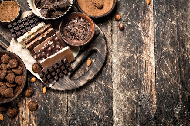 Barras de chocolate com trufas e cacau em pó em fundo de madeira