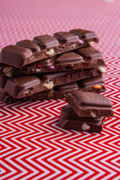 Barras de chocolate tiro vertical close-up em fundo vermelho e branco. Fundo ondulado vermelho e branco.