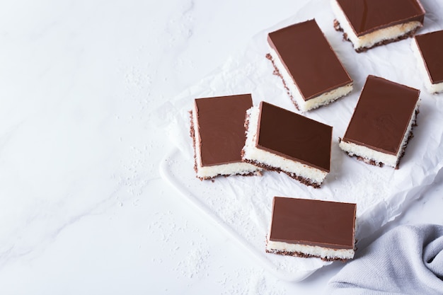 Barras de coco vegano cru orgânico e orgânico de energia saudável caseiro com chocolate na mesa da cozinha