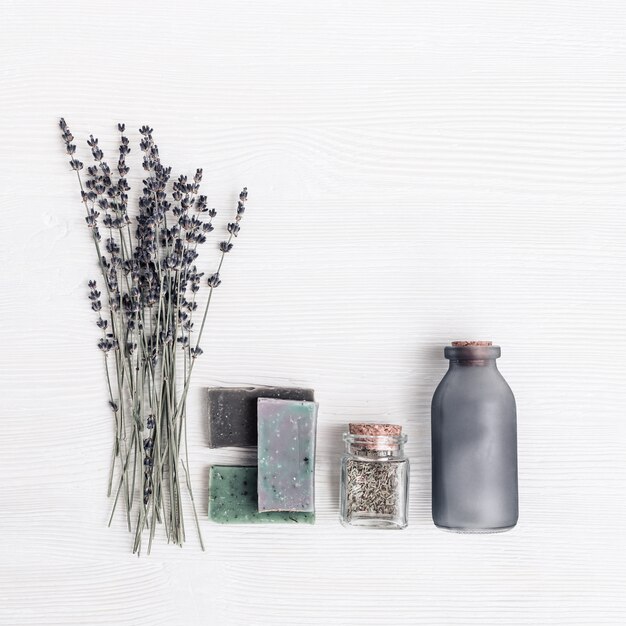 Barras de sabão artesanal brilhante, flores secas de lavanda e jarra de vidro com ervas aromáticas.