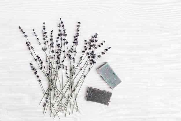 Barras de sabão artesanal com ingredientes orgânicos naturais, flores de lavanda secas na mesa de madeira branca