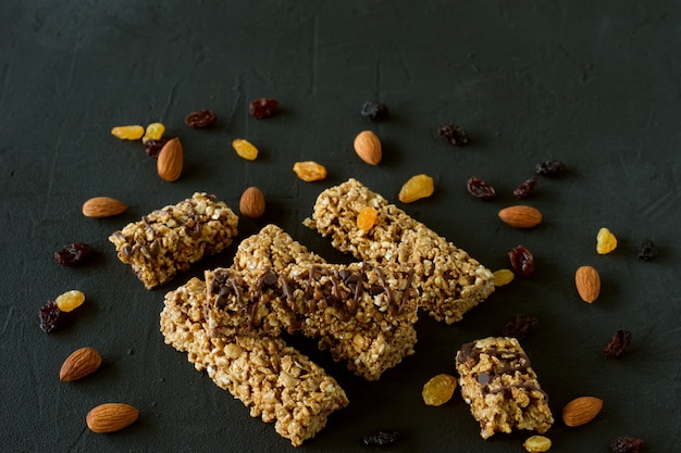 Barras energéticas de granola caseira com amêndoas e passas em fundo preto. Comida saudável.