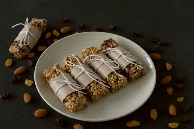 Barras energéticas de granola caseira com amêndoas e passas no alimento saudável preto.