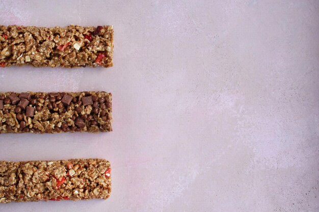 Foto barras de fitness de cereales con bayas sobre un fondo morado con espacio de copia