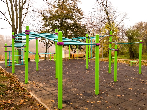 Barras horizontales y equipo deportivo moderno para hacer ejercicio en un campo deportivo vacío en un parque de la ciudad en una mañana nublada de otoño