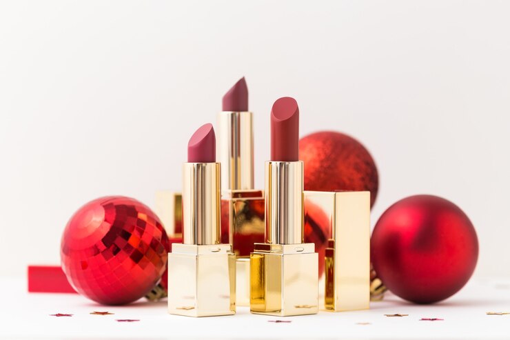 Barras de labios en estuche dorado y bolas rojas de Navidad.