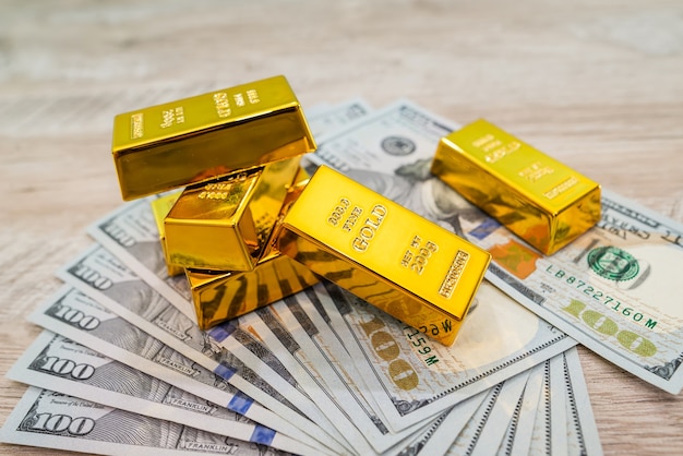 Barras de oro en billetes de dólar americano, concepto de ahorro financiero