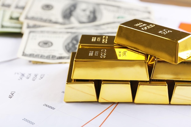 Barras de oro con billetes de dólar sobre fondo de papel