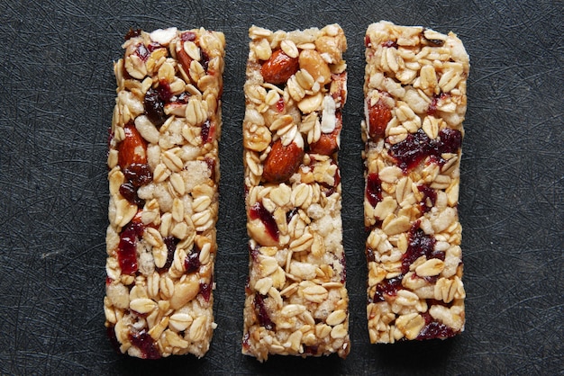 Foto barras de proteína de avena y pasas de almendra sobre fondo negro