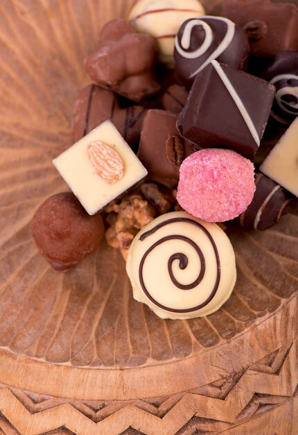 Barras rotas de chocolate con leche con nueces y bayas sublimadas y caramelos de chocolate sobre fondo de madera rústica, con espacio en blanco para la vista superior del texto, endecha plana