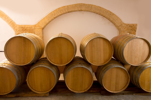 Barricas de roble de madera apiladas en bodega mediterránea.