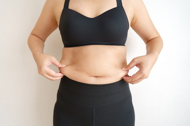 Barriga de gordura corporal de mulheres. Mão de mulher obesa segurando a gordura excessiva da barriga. conceito de estilo de vida dieta