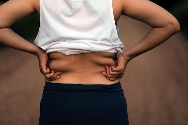 Foto barriga de gordura corporal feminina mão de mulher obesa segurando o conceito de estilo de vida de dieta de gordura excessiva da barriga para reduzir a barriga e moldar o músculo estomacal saudável