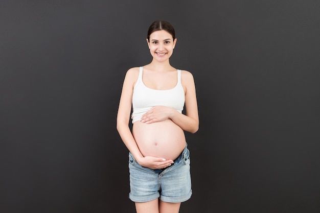 Barriga de grávida nua vestindo jeans abertos em fundo colorido com espaço de cópia Conceito de gravidez