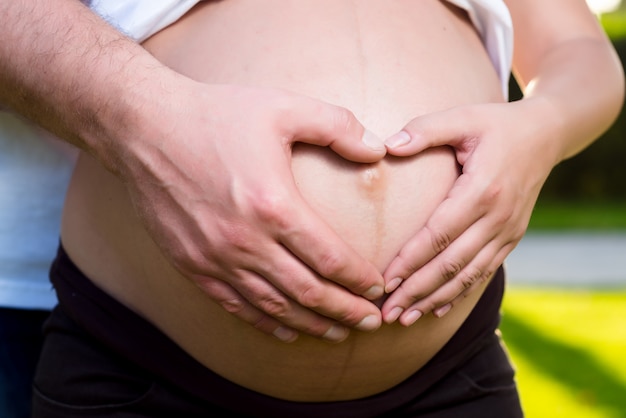 Barriga de mulher grávida com as mãos do marido