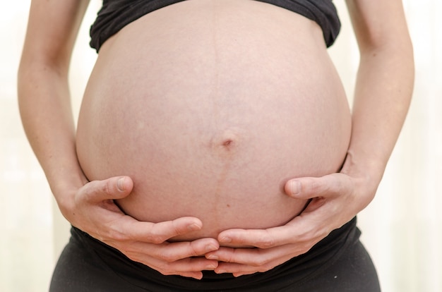 Barriga de mulher grávida com as mãos