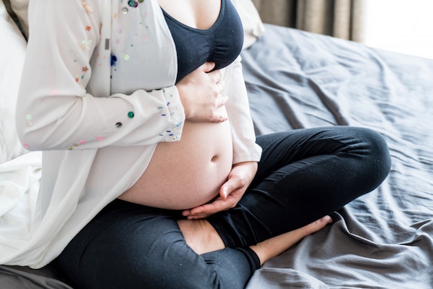 Barriga de mulher grávida com as mãos