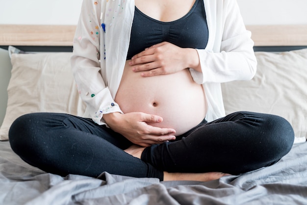 Barriga de mulher grávida com as mãos