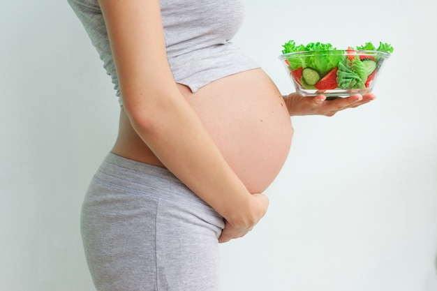 barriga de mulher grávida e salada de legumes