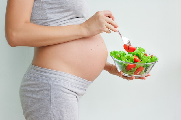 barriga de mulher grávida e salada de legumes