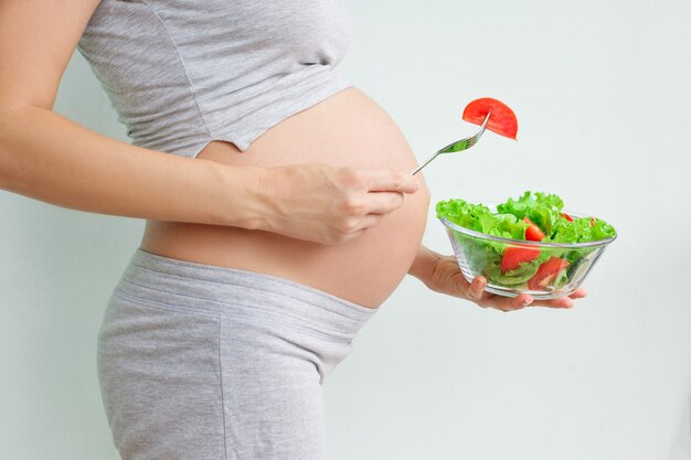 barriga de mulher grávida e salada de legumes