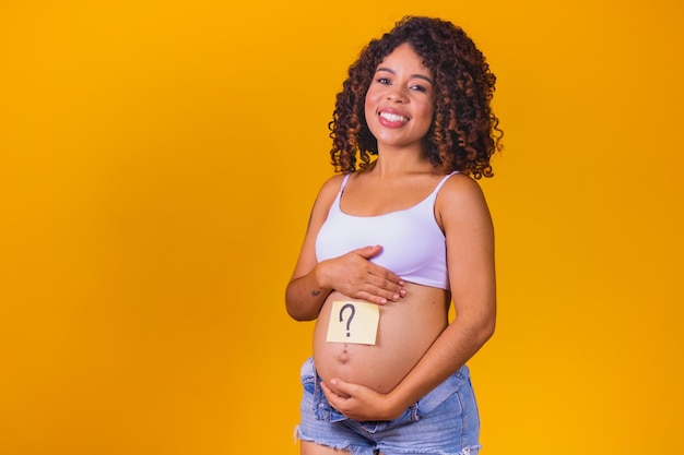 Barriga de uma jovem grávida com um adesivo branco e uma pergunta (conceito de menino ou menina).