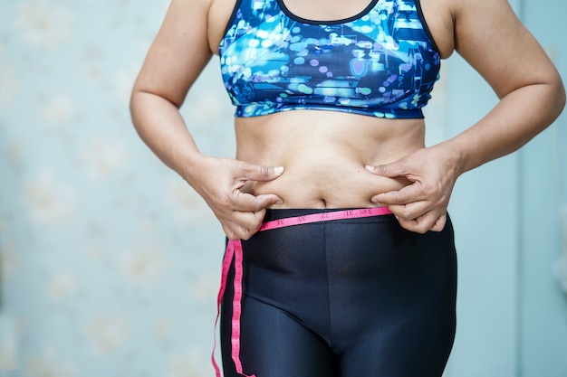 Barriga gorda da mostra asiática excesso de peso da mulher no escritório.