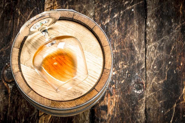 barril con una copa de coñac. Sobre un fondo de madera.