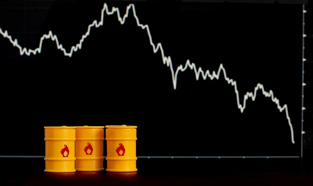 barriles de petróleo y gasolina en el fondo de una pantalla con un gráfico descendente